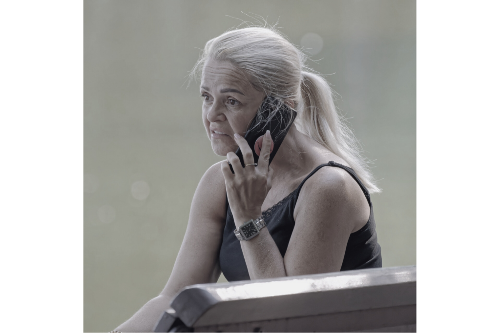 woman grimaces on phone thinking about someone faxing on a flip phone.